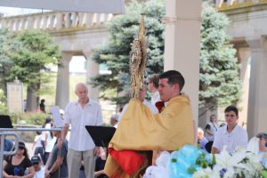 Father Jon Thomas, , offers Eucharistic benediction at the Kennedy Plaza following the ceremony at the surf.